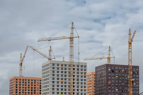 Tall construction cranes build tall houses