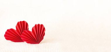two red paper corrugated hearts on a warm knitted background
