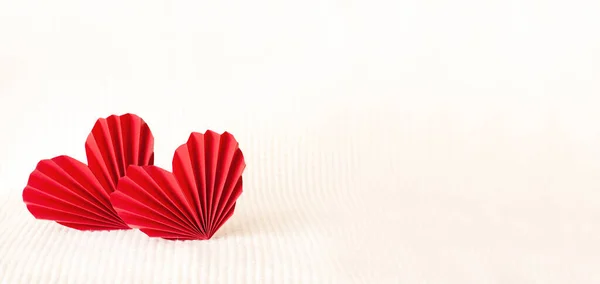 Two red paper corrugated hearts on a warm knitted background — Stockfoto