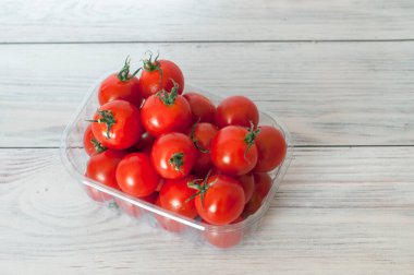 Tahta bir arka planda konteynırda taze domates, süpermarket.