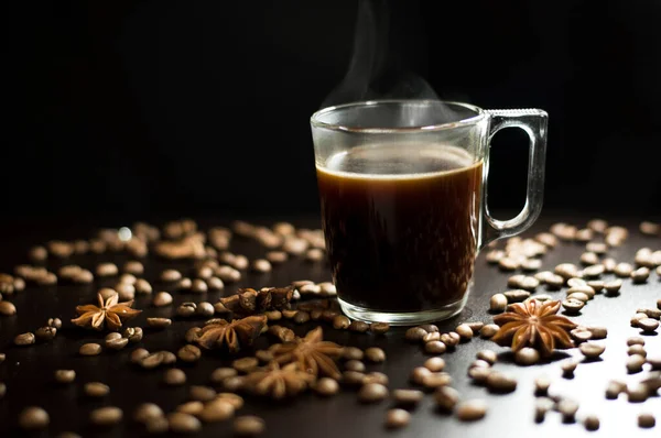 A cup of coffee on a black background with grains and badyan — Stock Photo, Image