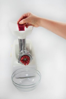 Adam elektronik et öğütücüsüne bir parça kırmızı et koyar.