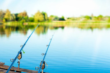 Nehirdeki eski bir balıkçı köprüsünde iki olta, bir adam dinleniyor, güzel bir manzara, bulanık bir arka plan. Yüksek kalite fotoğraf