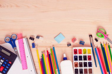 paints, pencils, scissors, glue and other accessories on a wooden background with a place for text, the concept of returning to school. High quality photo