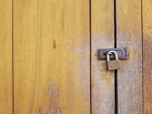 Close up of old yellow color painted door locked by a traditional old key to keep security  and safety. Home accessories and old way lifestyle in modern living.