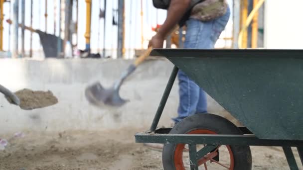 Arbetare kastar sand i vagnen — Stockvideo