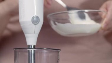 Kadın sos yapmak için bardağa ekşi krema koyar.