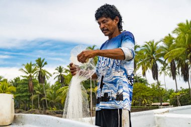 Konsantre balıkçı kıyıda ağını hazırlıyor. Kosta Rika kıyı manzarası.