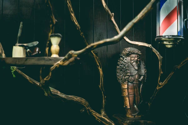 Barber shop light, wooden statuette, razor, brush and antique pipe on a barber shop shelf