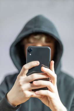 Genç kızın elinde bir cep telefonu var.