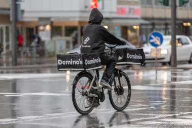Domino 'nun pizza teslimatçısı yağmurda bisikletli.