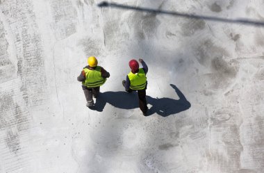 İnşaat alanında yürüyen iki işçinin hava görüntüsü