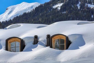 Alplerdeki karla kaplı bir çatıdaki yatakhane pencereleri.