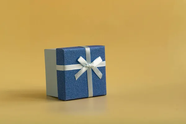 The gift is tied with a soft green ribbon on a yellow background — Stock Photo, Image