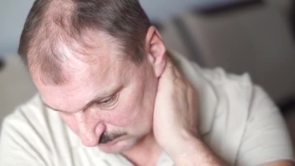 Un uomo anziano baffuto con testa pelata strofina e massaggia le articolazioni del collo con sintomi di dolore nella spondilosi cervicale, osteoartrite, stenosi, spasmi muscolari. Concetto di assistenza sanitaria, medicinali — Video Stock