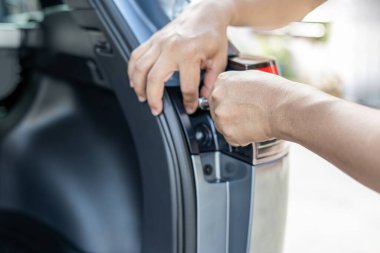 Close up hand a man use block wrench remove bolt of car tail lights are being disassembled with the car body Maintenance of lighting systems for safety concept