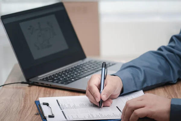 A man use a pen writing on the white paper clip board file in service concept and laptop on table in work office