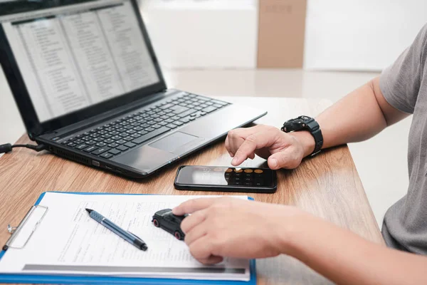 Service staff use smartphone calculate cost of repairing the car from the damage assessment document and use laptop on table office service center