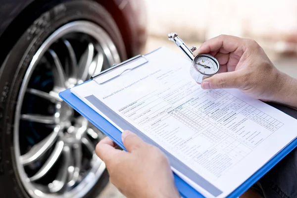 A man hold air pressure gauge check tire air pressure and memo in checklist in service check of car basic maintenance