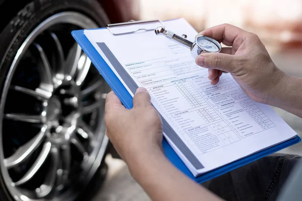 A man hold air pressure gauge check tire air pressure and memo in checklist in service check of car basic maintenance