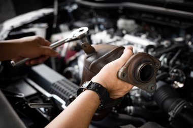 Close up old catalytic converter in hand Car service man and holding a wrench for remove part in engine room of car , service and maintenance concept in garage