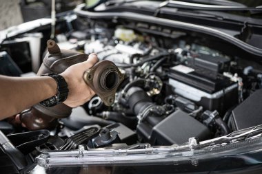 Eldeki eski katalitik dönüştürücüyü kapat. Teknisyen motor benzini tozunu kaldırdı. Arka plandaki motor odası ve servis konseptinde filtrede tıkandı.