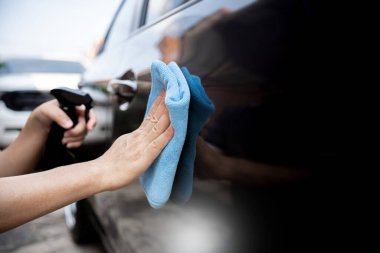 Araba temizleme konsepti, mikrofiber bez ve temiz sprey ağdası tutan bir adam yıkama yüzünden arabanın yüzeyi ile ilgilenir. 