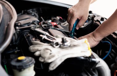 Araba servisi çalışanı, motor dairesindeki arabanın bir kısmını sökmek için tornavida ve motor servisi konseptinde anahtar ve eldiven kullanır.