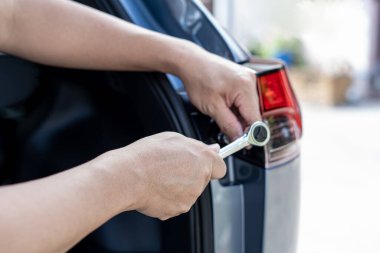 Yakın el, blok anahtarı kullanan bir adam araba sürgüsünü kaldırıyor. Arka farlar, güvenlik konsepti için aydınlatma sistemlerinin bakımıyla birlikte sökülüyor.