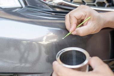 El ele tutuşup araba boyası tamiri için boya yapan bir adam bir kazadan sonra kendi başına yapılabilen temel araba servisi. 