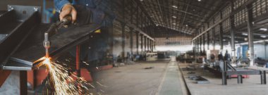 Endüstri işleri konsepti tel ekran fotoğrafında gaz kesicinin kafası tutuluyor ve imalat alanında çelik plakayı kesiyor ve arka planda bulanık bir fabrika var.