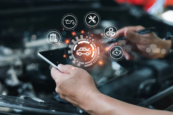 Car business concept and technology on virtual screen, Serviceman working onsite use tablet check service cycle for maintenance of car with the engine room in the background, Smart work of car service