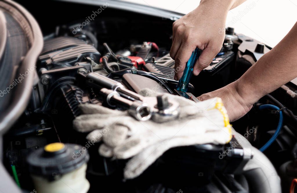 Car service man use screwdriver to remove part of the car in the engine room and wrench and glove on engine car service concept