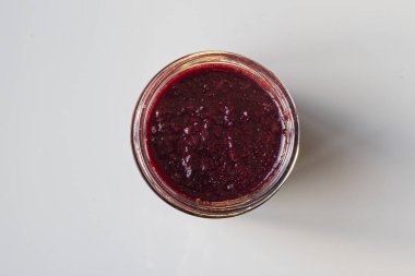 Masada çilek reçeli kavanozu var. Beyaz arka plan. Gastronomi.