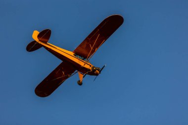 Gün batımında uçan küçük turuncu bir uçak.