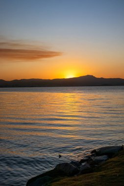 Güney Brezilya 'da Florianopolis' te gün batımı manzarası. Deniz kıyısındaki sahil yolunda. Doğa. Denizde kayalar. Dağlar.