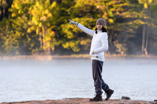 Женщина созерцает туман над озером на холодном рассвете. Стиль жизни.