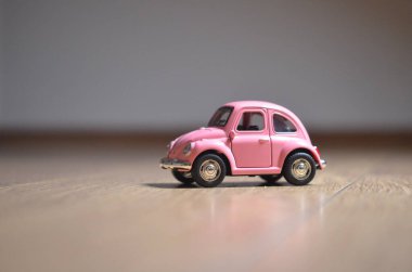 Ahşap zeminde pembe oyuncak araba.