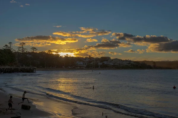 Haven Terrigal sahilindeki tepede gün batımı. Atlayan çocukla birlikte.