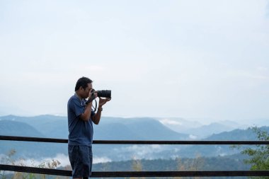 Erkek fotoğrafçı kamerasını kullanıyor. Manzara alıyor. Kârlı, seyahat konsepti..