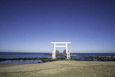 Fukuoka, Japonya 'daki beyaz torii kapısının vahşi manzarası, Itoshima' daki Sakurai Futamigaura 'nın açık mavi gökyüzü ve güneşli günü. Aşk geçmişi olan denizdeki en güzel beyaz torii.. 