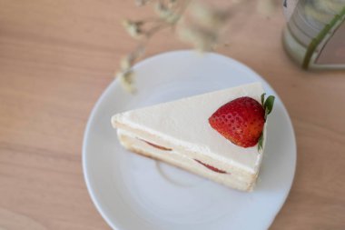 Çilekli kekin üst görüntüsü bulanık katmanlı kırbaç ve bulanık ön plan çiçekli wodden masa.