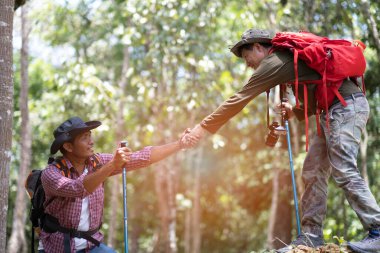 Dostu, arkadaşının tepenin zirvesine tırmanmasına yardım eder. Mutlulukla, arkadaşlıkla, dağ yolculuğu konseptiyle..