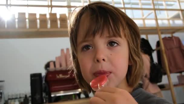 Vorschulkind isst Lutscher stehend in Garderobe-Nahaufnahme — Stockvideo