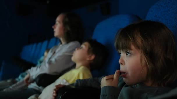 Mamá mira la película con hijos sentados en la sala de cine oscuro — Vídeos de Stock