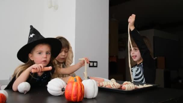 Дети в костюмах на Хэллоуин готовят вместе за столом — стоковое видео