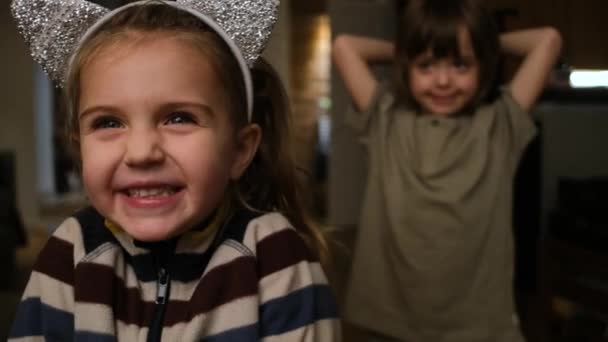 Glædelig lille pige med legesyg bror i stuen – Stock-video