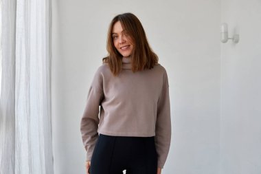 Beyaz duvarda kapüşonlu neşeli kadın