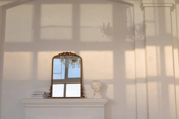暖炉の白い壁の鏡と像 ストック写真