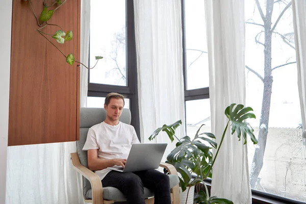 Man working using laptop at home while sitting in chair — стоковое фото